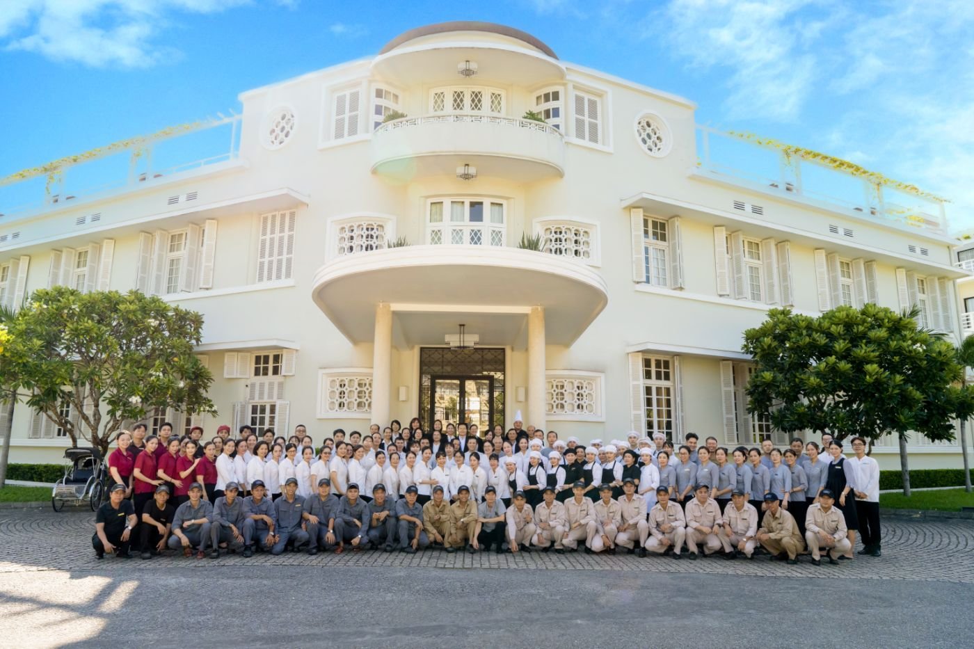 One team, one home: the staff of Azerai La Residence, Huế, gathered before the mansion in 2026.