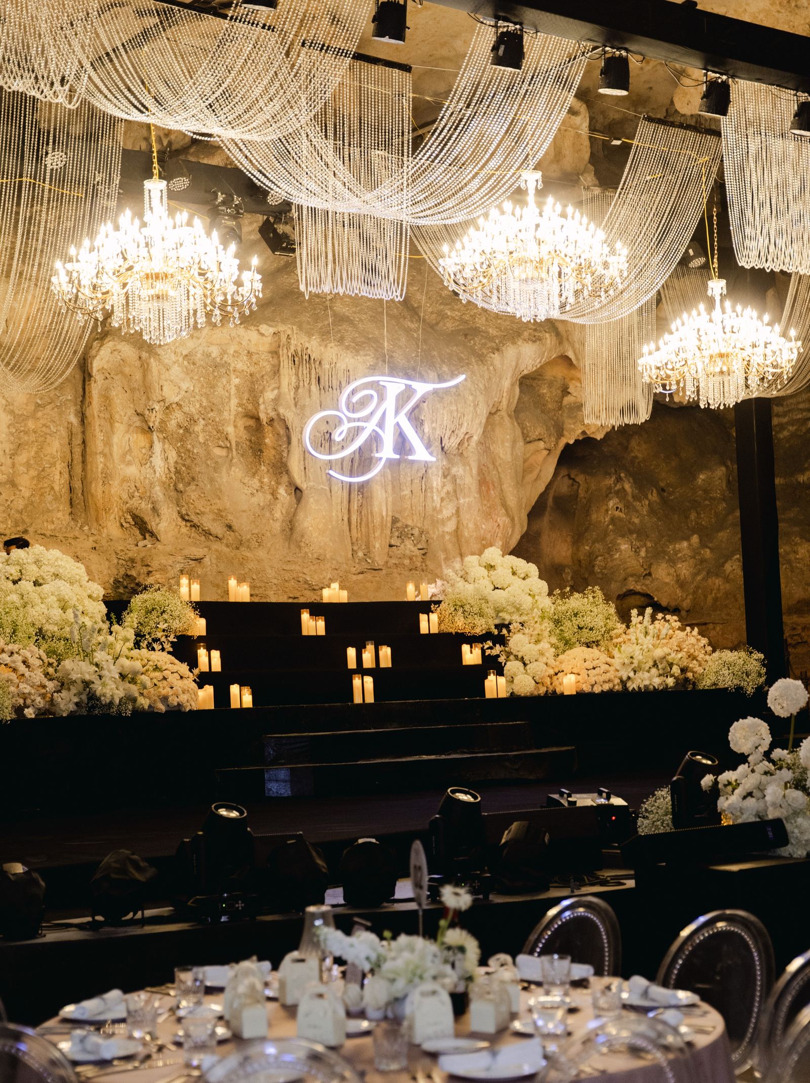 A wedding banquet beneath chandeliers and the couple's monogram in the main chamber.