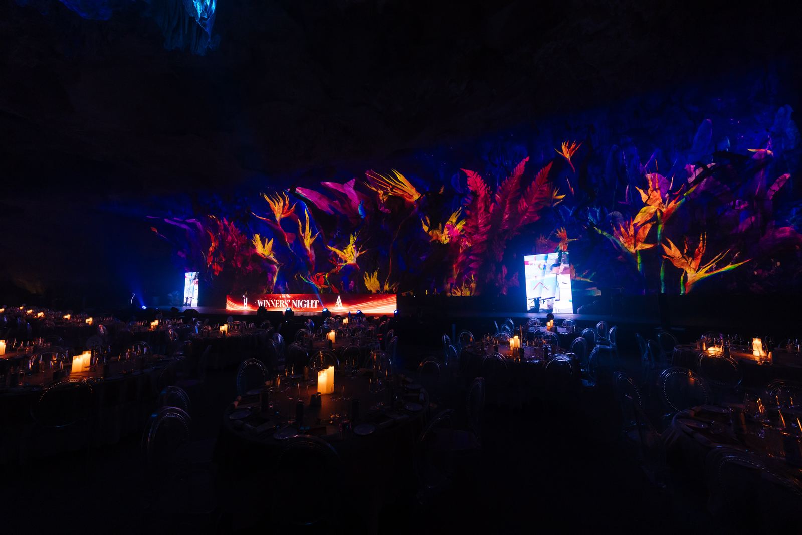 Lighting and projection move across the stone as dinner unfolds beneath the formations.