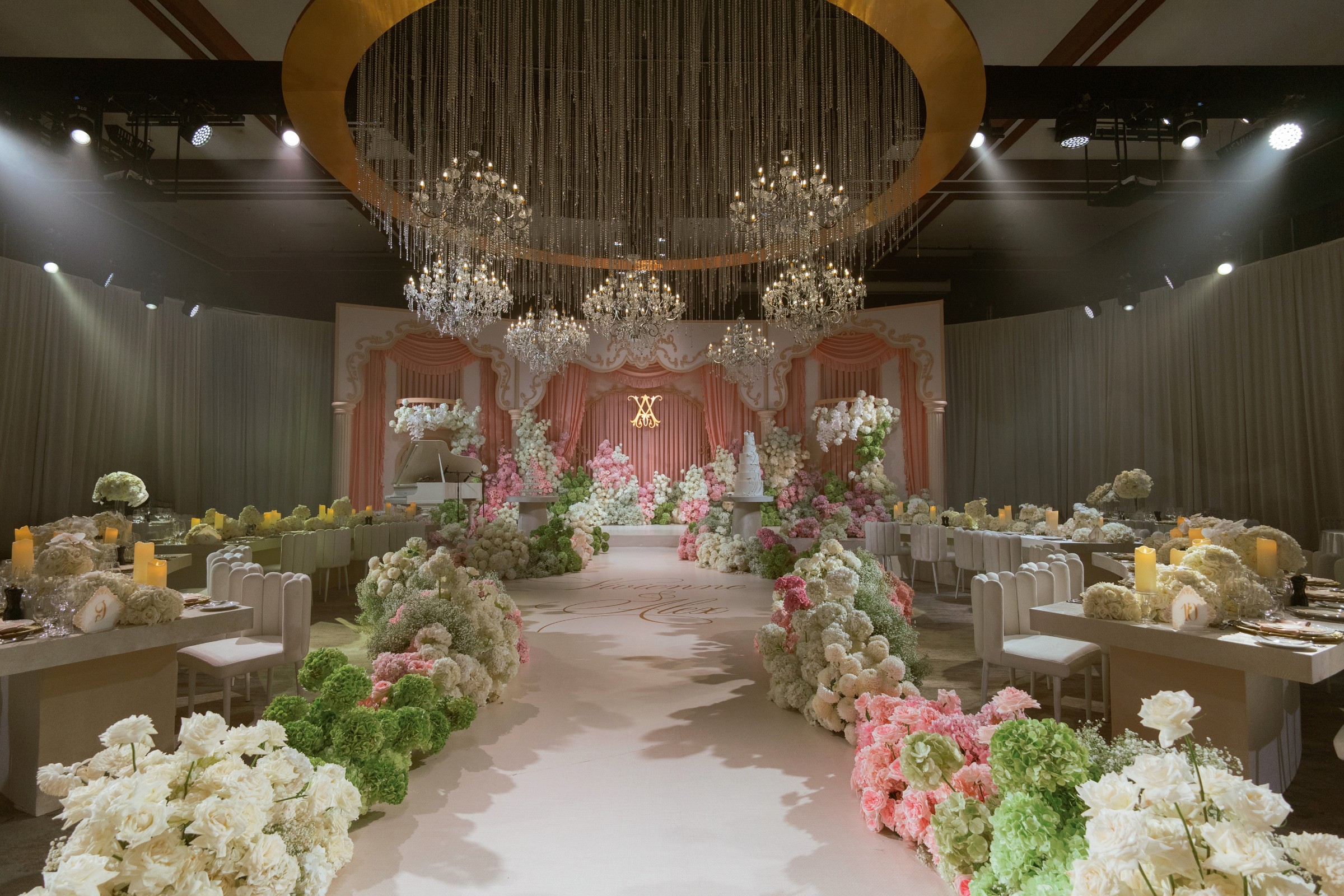 The Grand Ballroom on the fourth floor, set for a seated reception with a lit stage and floral aisle.